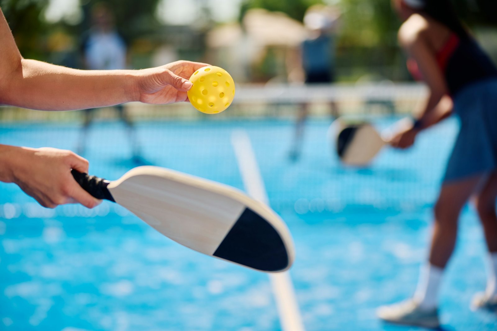 Close up of woman serving the ball while playing pickleball.