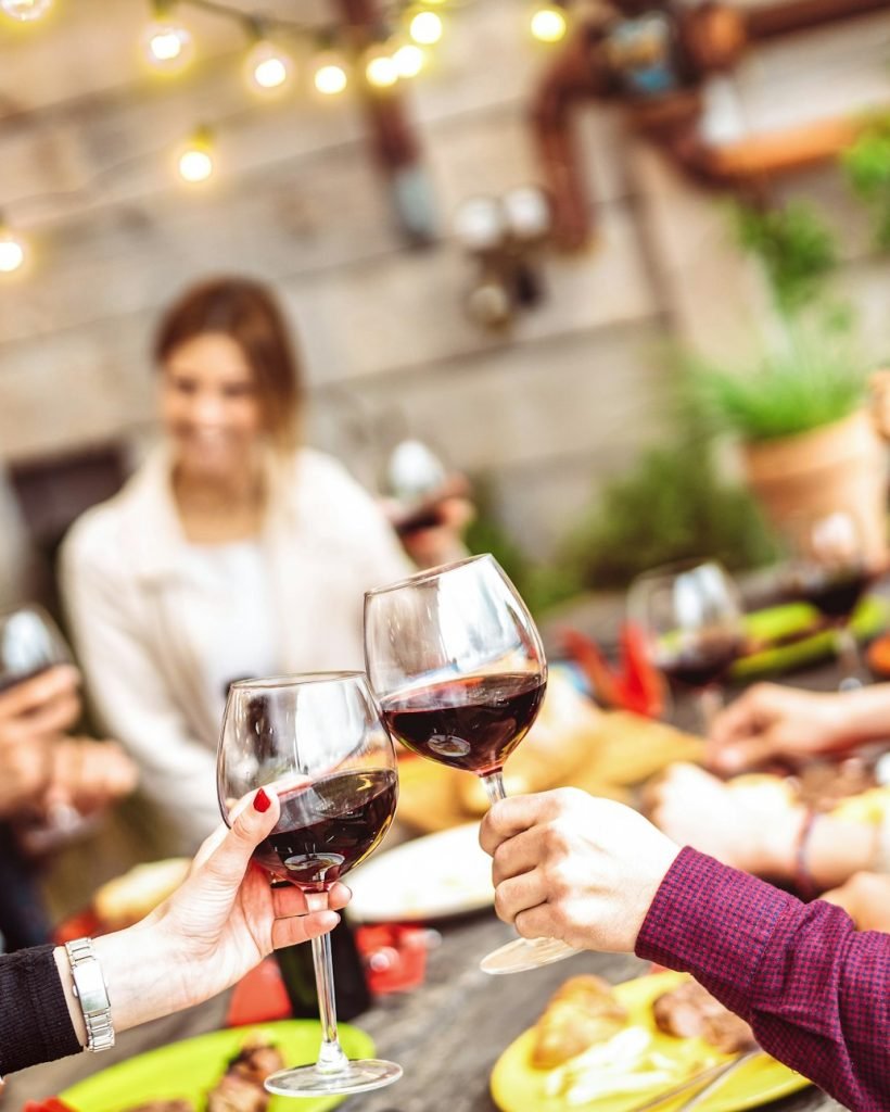 Happy friends having fun drinking red wine on balcony at private dinner party