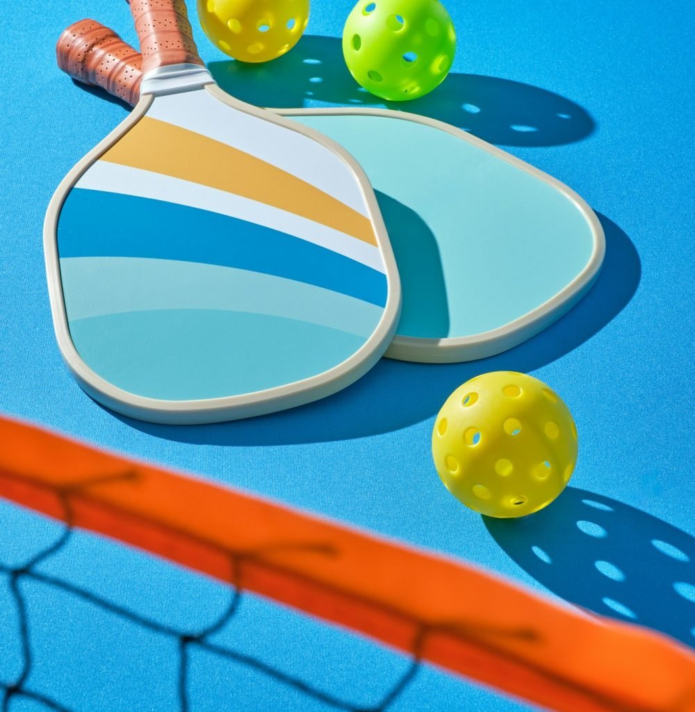 pickleball paddles with balls to the side on a blue background illuminated with hard light